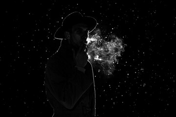 dark silhouette of a man in a hat Smoking a cigarette in the rain