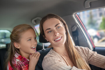 Smiling daughter talking to her mom from backseat of car