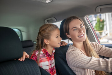 Happy daughter talking to her mom from backseat of car