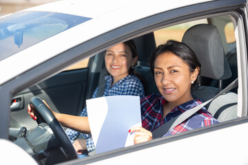 Portrait of smiling Peruvian woman driving car, holding blank white paper with copyspace