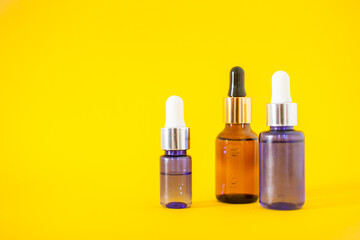 Cosmetic bottles with serum on a yellow background. Cosmetology and beauty concept.