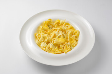 Delicious vegetarian dish of pasta with cheese served in a white plate over white background.