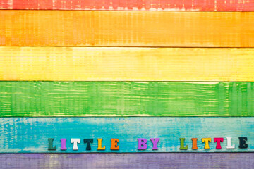 lgbt rainbow colors wooden background with inscription little by little