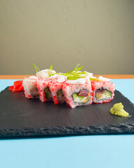 Sushi set California or Philadelphia served on a black board over pastel blue background.
