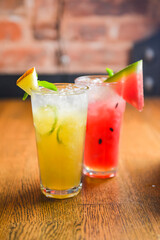 Watermelon and melon smoothies garnished with watermelon slices and mint leaves served in a glass on rustic wooden table