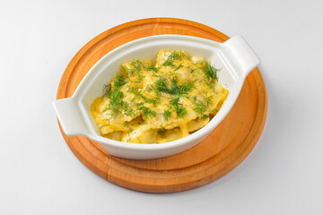 Ravioli dumpling with fresh greenery served in a white pot over white background. Isolated on white.