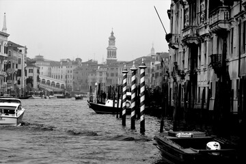Venice, Italy, December 28, 2018 evocative black and white image of Venice canal with traffic of boats 
and foreshortening of the Rialto Bridge