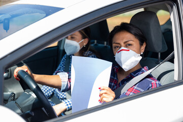 Hispanic women wearing personal protective equipment while driving a car