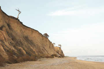 Clay slopes on sand beach against blue sky