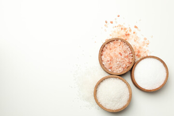 Wooden bowls with salt on white background, top view