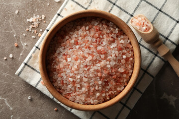 Bowl of pink himalayan salt, napkin and scoop on gray background