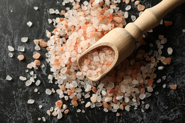 Wooden scoop with pink himalayan salt on black smokey background