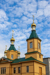 Fototapeta na wymiar The building of the Orthodox Church against the background of the sky and clouds. Church of St. Sergius of Radonezh, city of Magadan, Magadan Region, Russian Far East, Siberia.