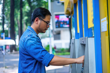 Close-up of man (wearing blue jean), using credit card to withdrawing money from ATM machine....