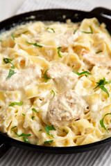 Homemade Chicken Fettuccine Alfredo in a cast-iron pan on a white wooden background, low angle view. Close-up.