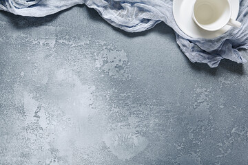 Empty tea cup and blue cloth on old surface background