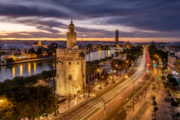 Fototapeta na wymiar Vista cinematica nocturna de la Torre del Oro de Sevilla con el Río Guadalquivir y Torre Sevilla al fondo