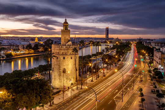 Vista cinematica nocturna de la Torre del Oro de Sevilla con el R&iacute;o Guadalquivir y Torre Sevilla al fondo