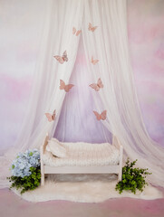 Pink newborn baby bed with flowers and butterflies in a photo studio
