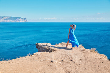Travel time and journey abroad concept, copy space. Lady in dress and hat posing on cliff top. Sea view and fresh air.