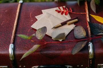 Craft paper envelopes and golden fountain pen on the vintagge suitcase. Letters and fountain pen. Autumn coziness.