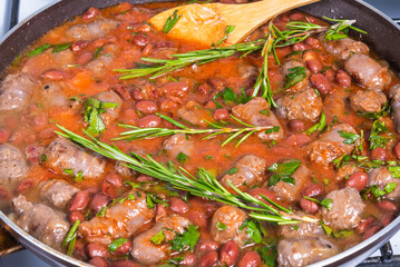 Cooking Texas cowboy dish, beef sausages with beans, onions in tomato sauce in a pan