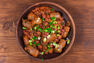 Traditional country texas cowboy dish, beef sausages with beans, onions in tomato sauce in a rustic...
