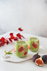 Obraz na płótnie Canvas Matcha green tea breakfast superfoods smoothie with figs in glasses. Side view, copy space. Japanese matcha tea drink, dessert. Healthy superfoods, detox, diet
