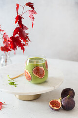 Delicious homemade Green matcha smoothie drink with bananas and figs in a glass. Side view, copy space. Detox, superfood recipe, vegan menu, healthy food.
