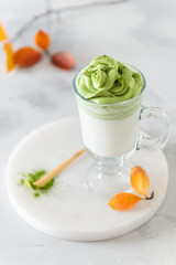 Dalgona Matcha Green Latte, a creamy whipped matcha in a glass on light background. Side view, close up. Matcha recipe, vegan menu, healthy eating, detox, super foods.