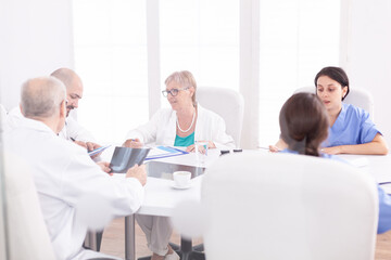 Obraz premium Academic meeting of expert doctors in hospital conference room. Clinic expert therapist talking with colleagues about disease, medicine professional