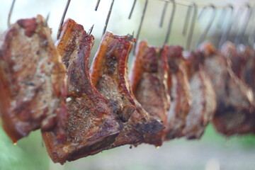 Smoked pork ribs hanging on metal hooks.