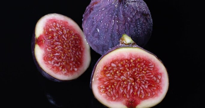 Fresh figs with water drops isolated on black background rotating