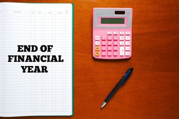 Flatlay picture of account manuscript book written End Of Financial Year with calculator and pen.