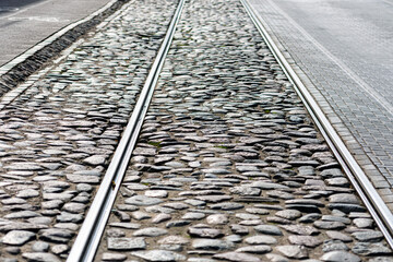 the iron rails for the tram on a cobblestone paved street