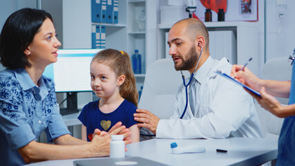 Fototapeta premium Caring medical doctor consulting girl in office with stethoscope checking breath. Specialist in medicine providing health care service consultation diagnostic examination treatment in hospital cabinet