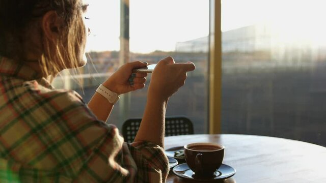 Close up of woman holds modern smartphone and taking pictures of her morning breakfast coffee and tasty croissant bun to share photos on social media resources
