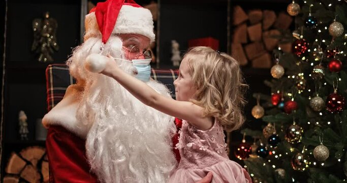little girl giving santa claus a medical mask