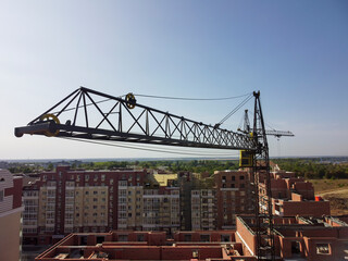 Crane over new buildings. Aerial view, cargo crane boom high in the sky.