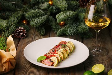 tuna steak with lime. sliced tuna steak in sesame on christmas background with glass of white wine