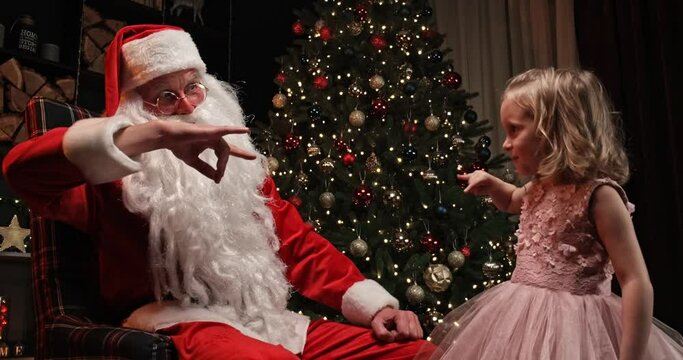 santa claus and a little girl near the christmas tree