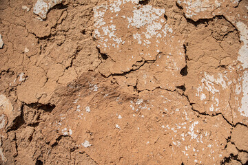 Close-up of the cracked wall of an old house made of clay mixed with straw. A clay house in the village. Handmade old way of construction. Countryside structures and architecture.