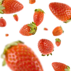 Many strawberries free falling on white background. Selective focus - shallow depth of field.