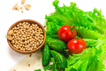 Chickpea beans in wooden bowl. fresh tomatoes, cucumbers, lettuce salad on tablecloth isolated on white background. Organic, healthy food concept