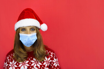 Fototapeta na wymiar girl in medical face mask, Santa hat and Christmas sweater on red background