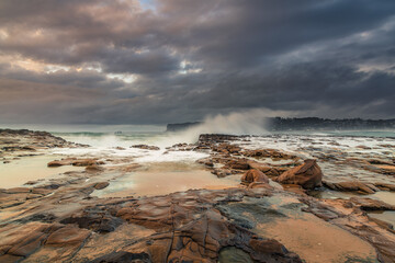 Rock platform, cascades and splashes with rain clouds by the seaside