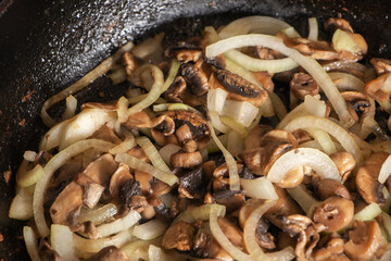 Champignons frying on the pan with onion
