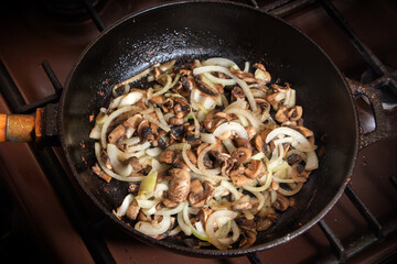 Champignons frying on the pan with onion