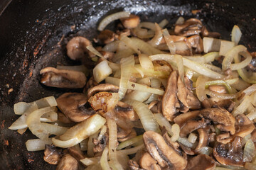 Champignons frying on the pan with onion