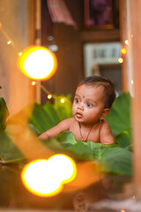 Cute indian little child playing with green leaf and colorful light